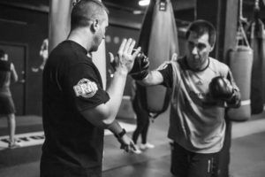 Entrenador boxeo corrigiendo posición de guardia